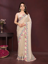 Woman wearing a beige saree with floral patterns against a dark background