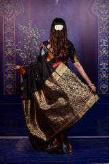 Woman in a traditional saree with a geometric pattern against a decorative blue wall.