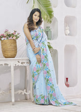 Woman wearing a floral saree in a decorated room with plants and a table.