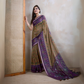 Woman wearing an olive green georgette saree featuring a striking purple geometric border and abstract patterns, paired with a matching blouse, traditional silver earrings, and stacked bangles. She stands elegantly in a contemporary studio setting with a textured woven screen, a neutral-toned wall, and a rustic wooden floor, showcasing graceful draping and a flowing pallu.