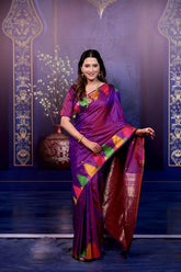 Woman in a colorful saree against an ornate blue wall.