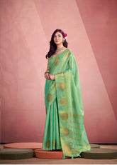 Woman wearing a green saree with gold patterns against a pink background