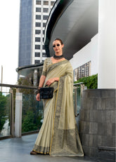 Woman in a saree standing in an urban setting with modern architecture.