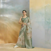 Woman in a green saree standing against a gradient wall