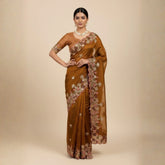 Woman wearing a brown saree with floral patterns on a beige background