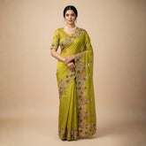 Woman wearing a green saree with floral patterns on a beige background