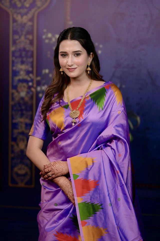 Woman in a traditional purple saree with colorful patterns against a dark background