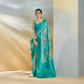 Woman wearing a teal saree with a blurred background