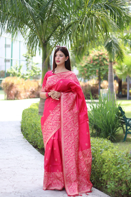 Woman wearing dark pink traditional weaving saree with intricate design posing elegantly in garden setting