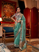 Model in deep teal saree with elegant zari work and colorful embroidered blouse, showcasing luxurious ethnic fashion in a regal setting