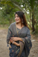 Woman wearing gray traditional weaving saree with intricate design in a lush garden background