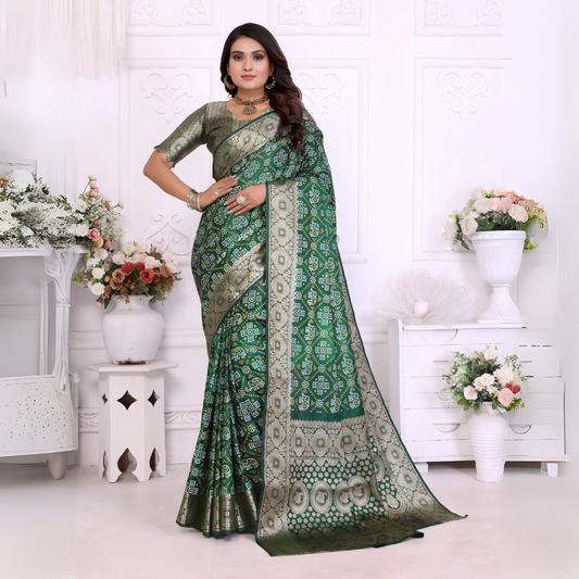 Woman wearing a green Banarasi silk saree adorned with intricate silver zari border and traditional woven motifs, paired with a matching silver blouse and classic jewelry. She poses gracefully in an elegant white room with decorative wall panels, white vases, and abundant pastel floral arrangements.