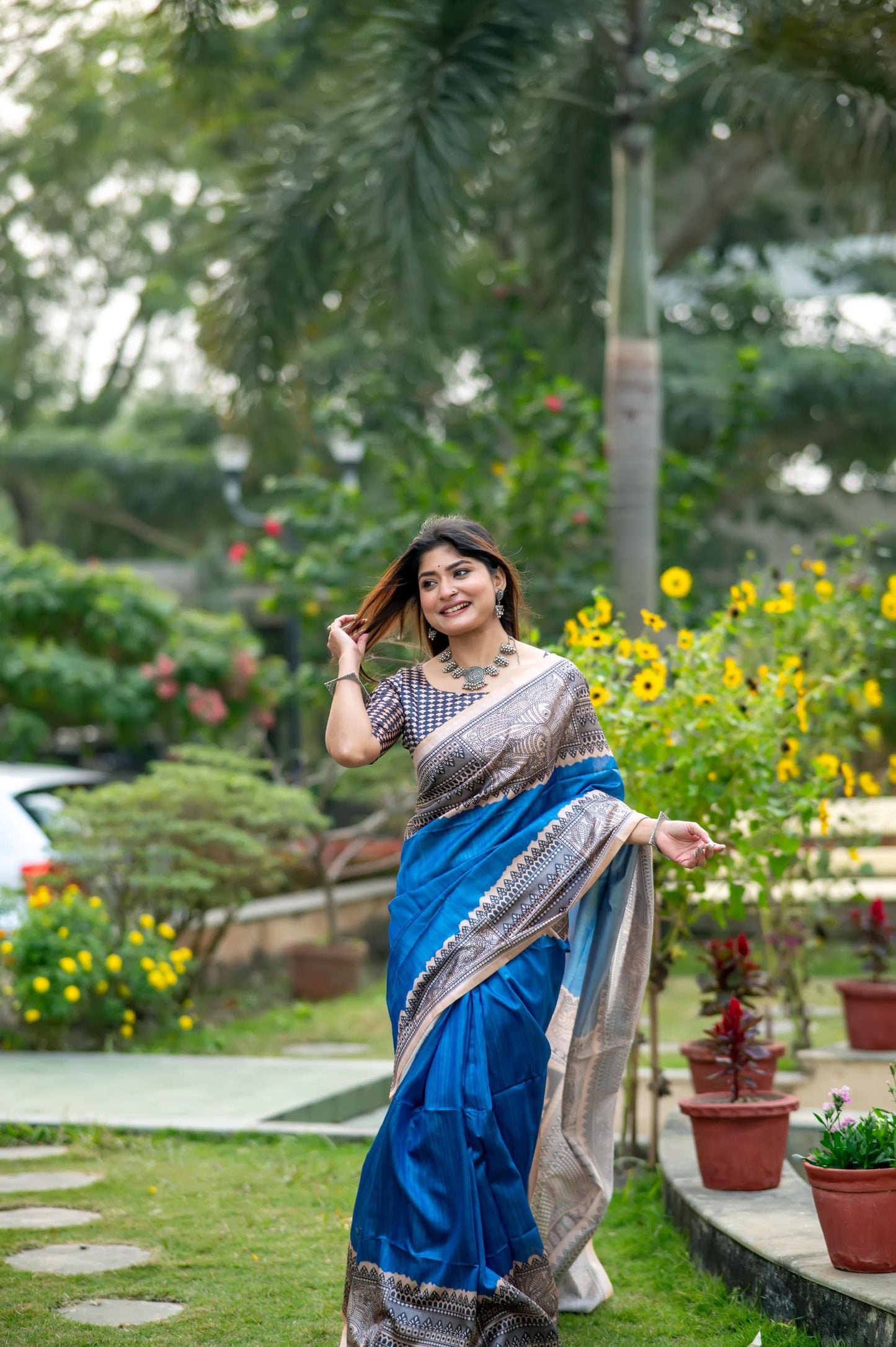 Woman wearing blue Madhubani print saree posing outdoors in traditional Indian ethnic outfit