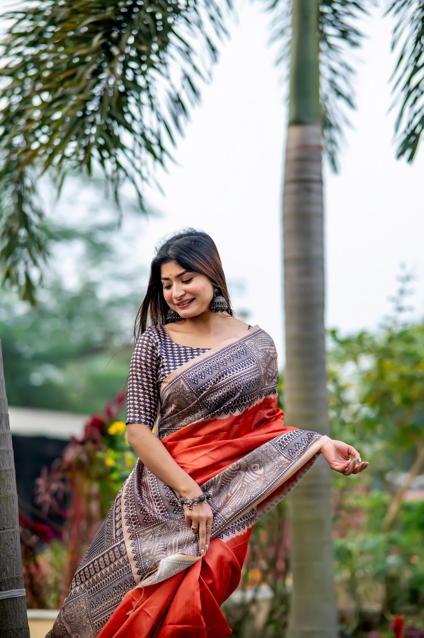 Woman wearing dark pastel red Madhubani print saree standing outdoors in traditional Indian ethnic attire