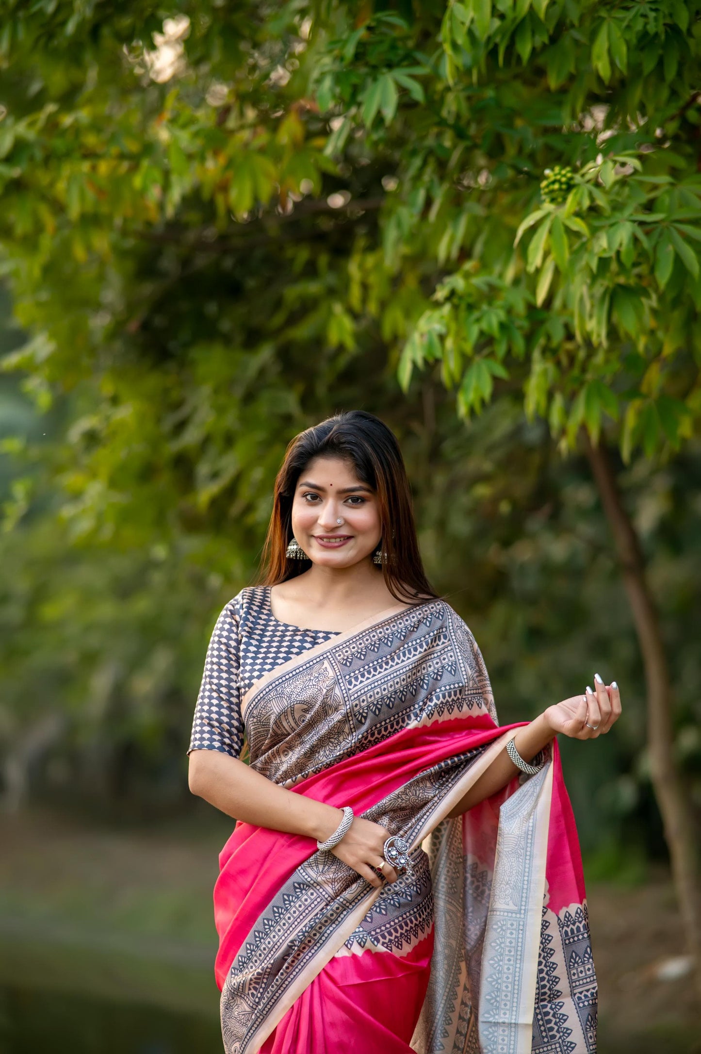 Woman in dark pink Madhubani print saree standing outdoors in elegant traditional Indian outfit
