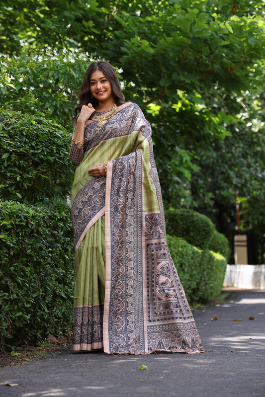 Woman wearing traditional olivine Madhubani print saree with intricate designs and ethnic jewelry in a green outdoor setting