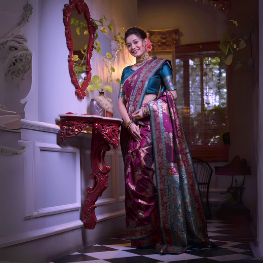 Woman wearing a magenta Banarasi silk saree with intricate gold and teal blue border, paired with a teal blue blouse and traditional jewelry, standing beside an ornate red mirror and console table in a vintage-inspired interior with checkered flooring and wooden blinds.