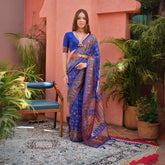 Woman wearing navy blue Kashmiri Jal weaving saree with intricate patterns in a lush green outdoor backdrop