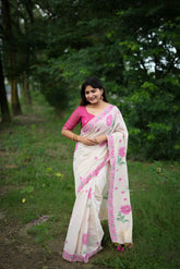 Woman in pink resham weaving saree with floral handloom design, styled traditionally in a lush outdoor setting