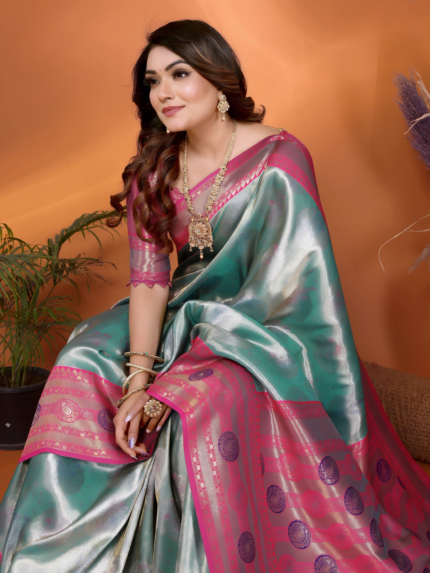 Woman wearing a traditional saree with a pink and green pattern against an orange background