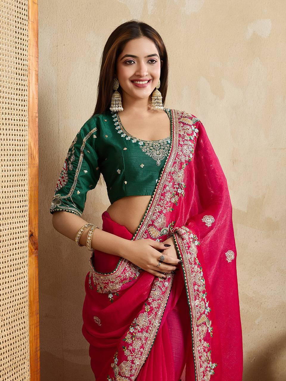 Woman wearing a royal purple silk saree with intricate pink and gold border and pallu, paired with a matching blouse and traditional gold jewelry, standing on a terracotta-tiled outdoor terrace with decorative plants