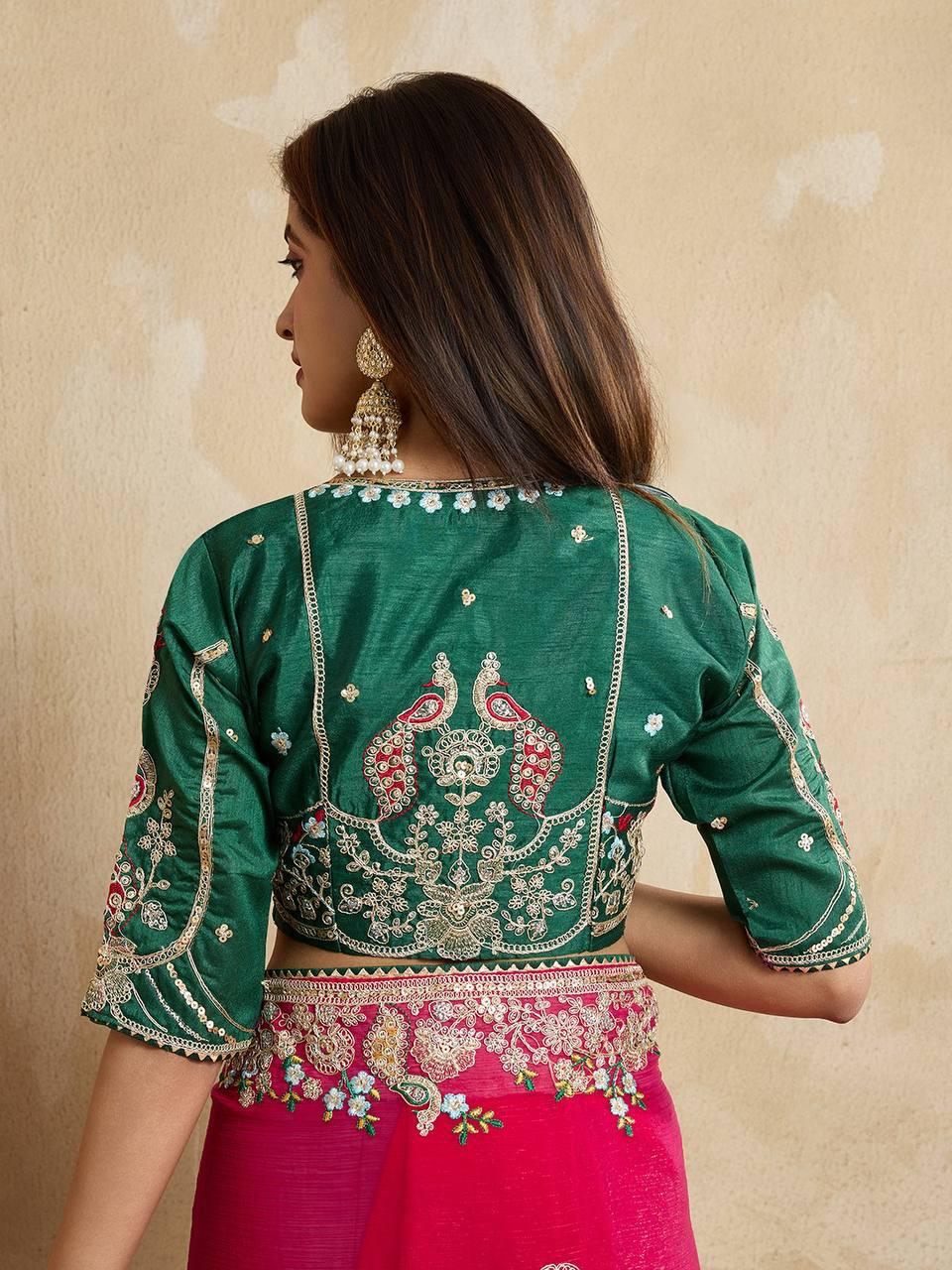 Woman wearing a royal purple silk saree with intricate pink and gold border and pallu, paired with a matching blouse and traditional gold jewelry, standing on a terracotta-tiled outdoor terrace with decorative plants and peach-colored walls