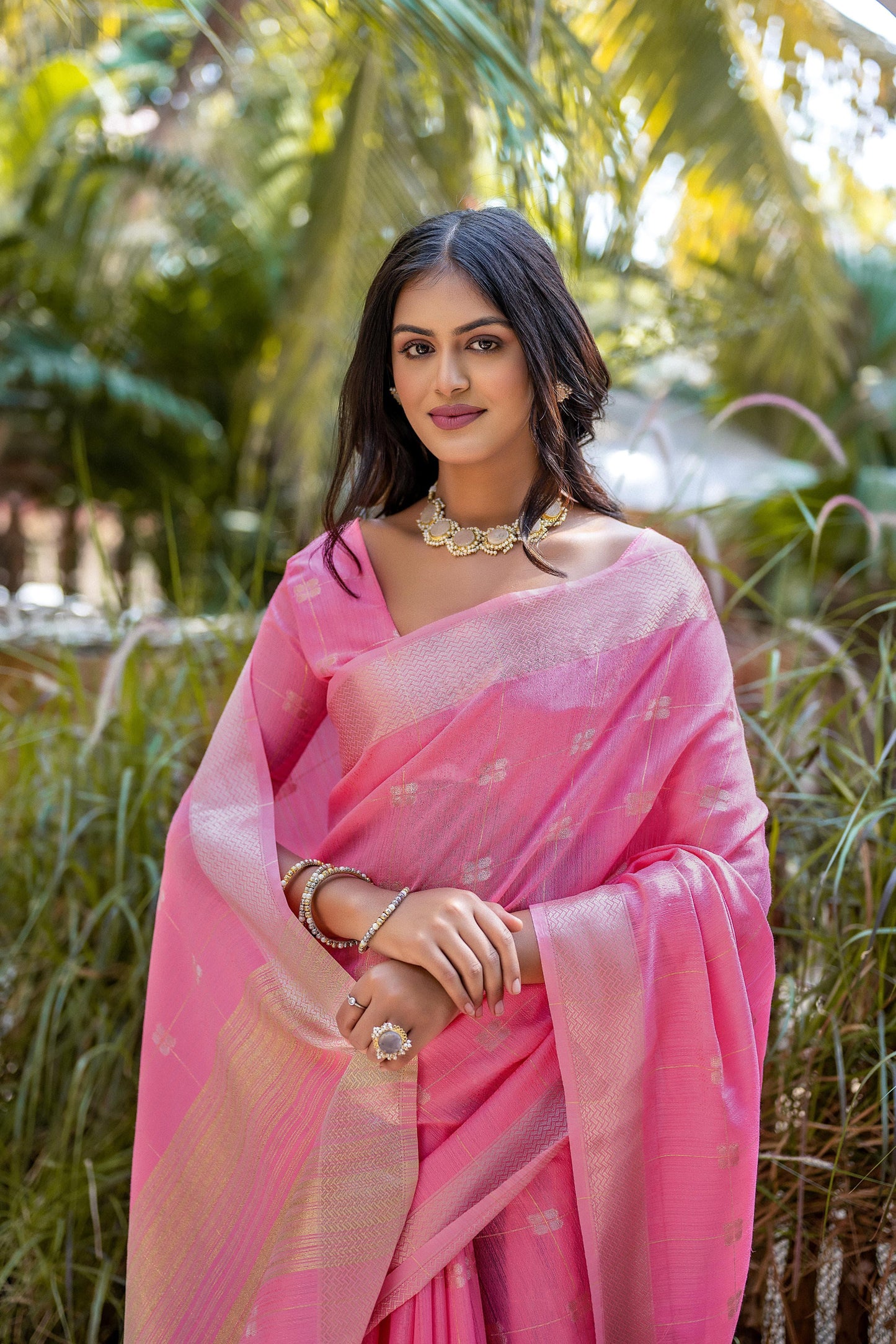 Woman wearing light pink Zari weaving saree standing outdoors in traditional Indian ethnic