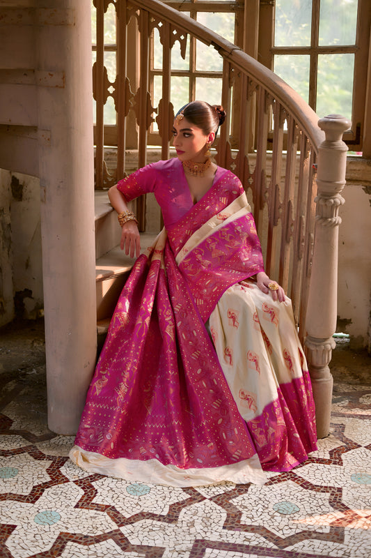  Woman wearing a vibrant pink and gold silk saree with traditional motifs, elegantly posing beside a vintage spiral staircase in a grand, historic interior with large arched windows, intricate railings, and distressed walls.