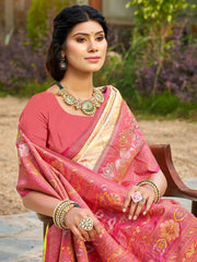 Woman in a pink saree with gold jewelry sitting outdoors.