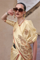 Woman wearing a cream saree with gold patterns and sunglasses against a neutral background