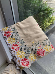 Beige fabric with floral embroidery held by a person outdoors.