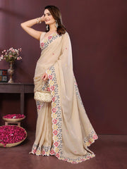 Woman wearing a beige saree with floral patterns against a brown background