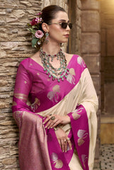 Woman in a pink saree with gold patterns against a stone wall.