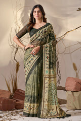 Woman wearing a traditional saree with intricate patterns against a natural background