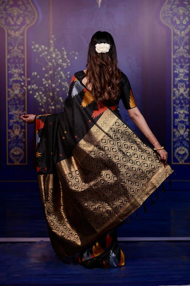 Woman in a traditional saree with a geometric pattern against a decorative blue wall.