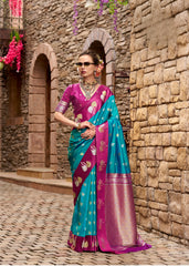 Woman in a colorful saree standing against a stone wall.