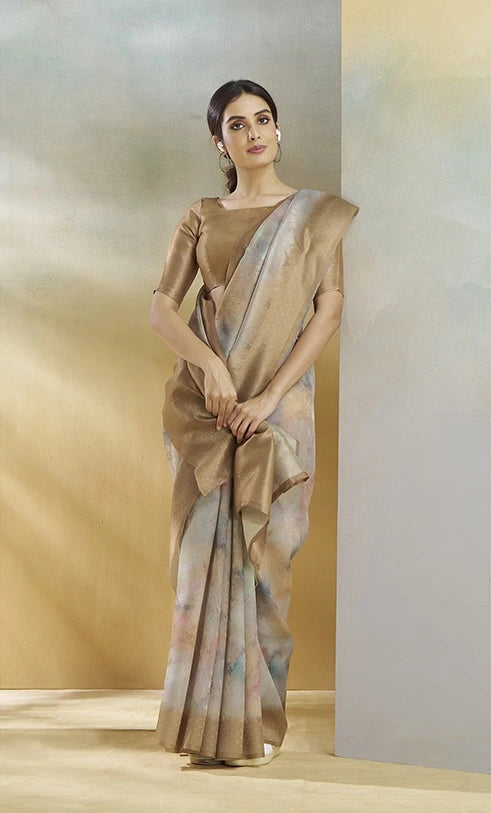 Woman wearing a beige saree with a plain background