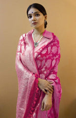 Woman in a dark pink jacquard work saree with gold border standing indoors in a sophisticated room with arched decor and vintage furniture accents