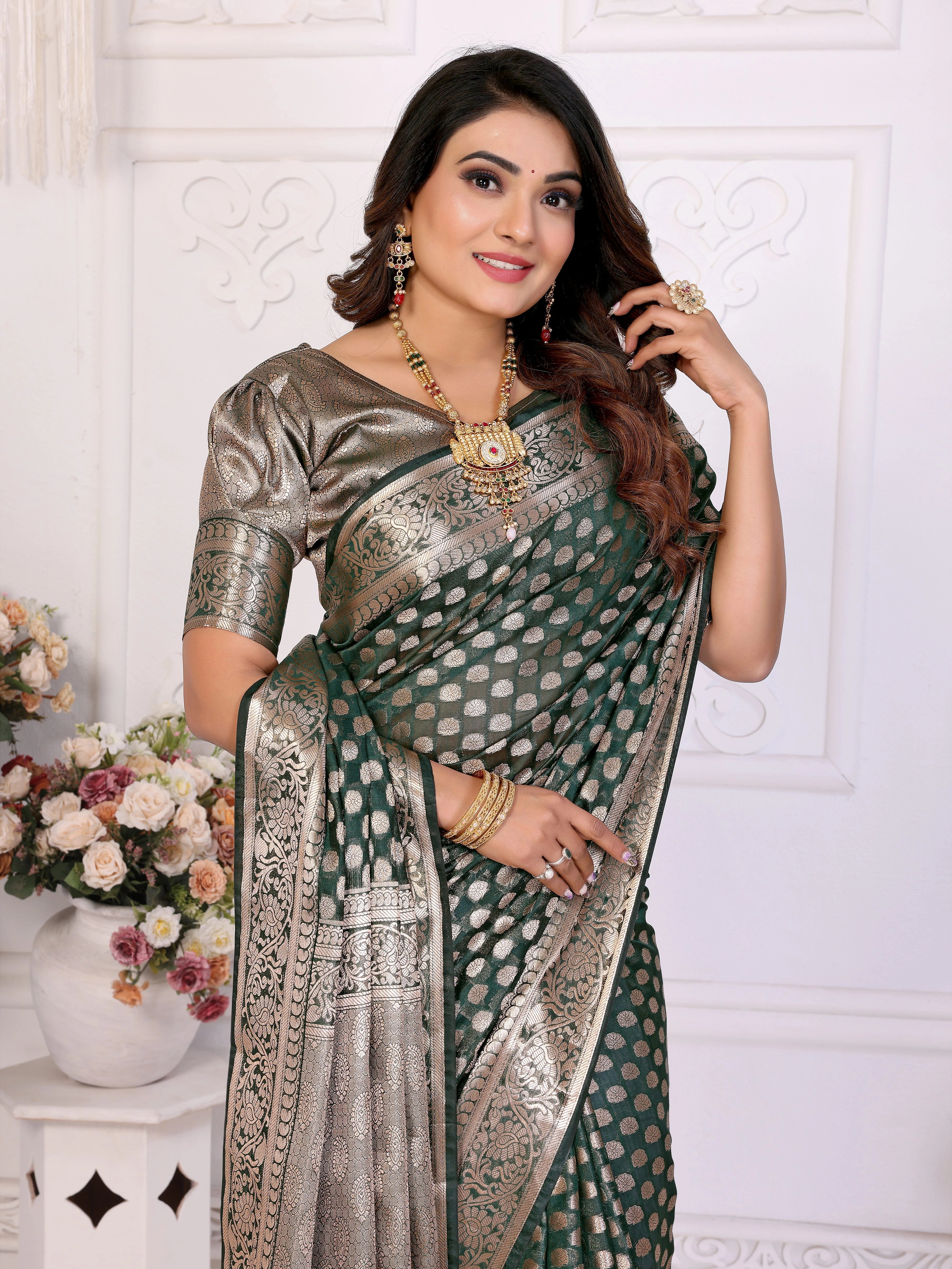 Woman wearing a traditional saree with jewelry against a white wall