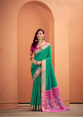 Woman wearing a green and pink saree with a beige wall background