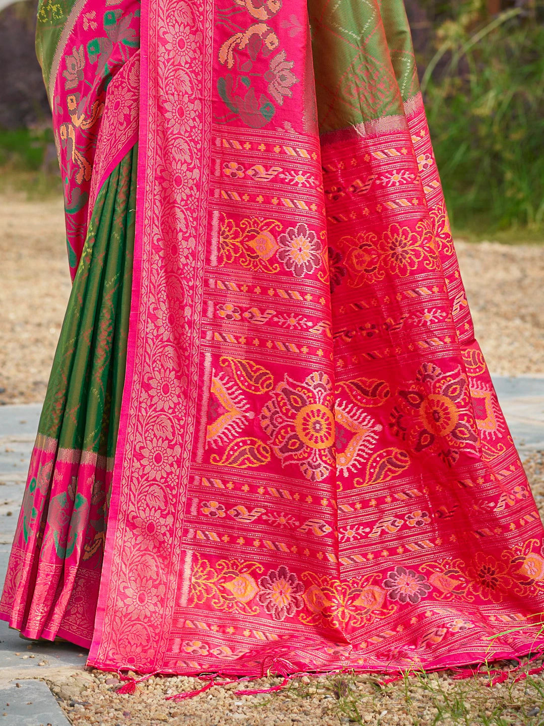 Traditional pink and green saree with intricate patterns on a natural background