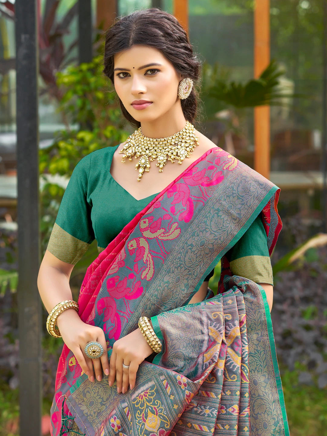 Woman wearing a traditional saree with a green blouse in an outdoor setting