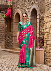 Woman in a pink and green saree standing in front of a stone building with arches.