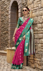 Woman in a pink and green saree standing against a stone wall.