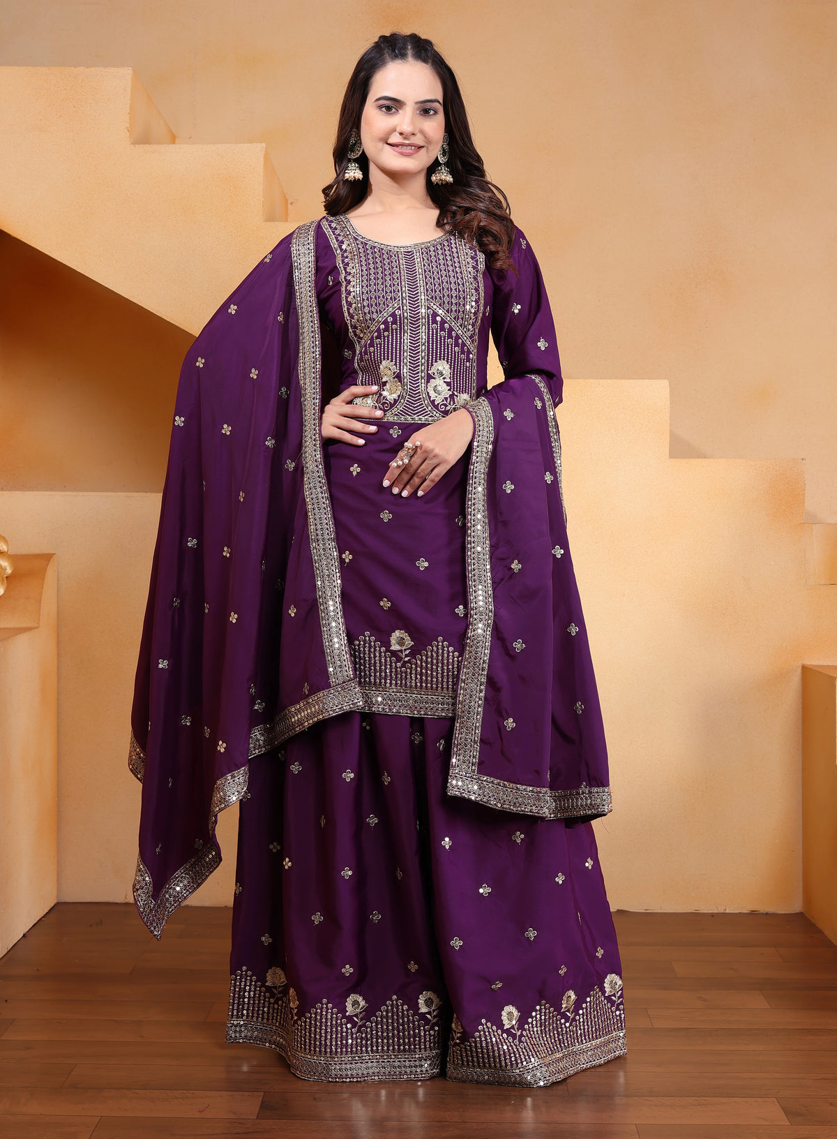 Woman wearing a purple traditional outfit with silver embroidery in a neutral setting