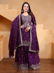 Woman wearing a purple traditional outfit with silver embroidery in a neutral setting