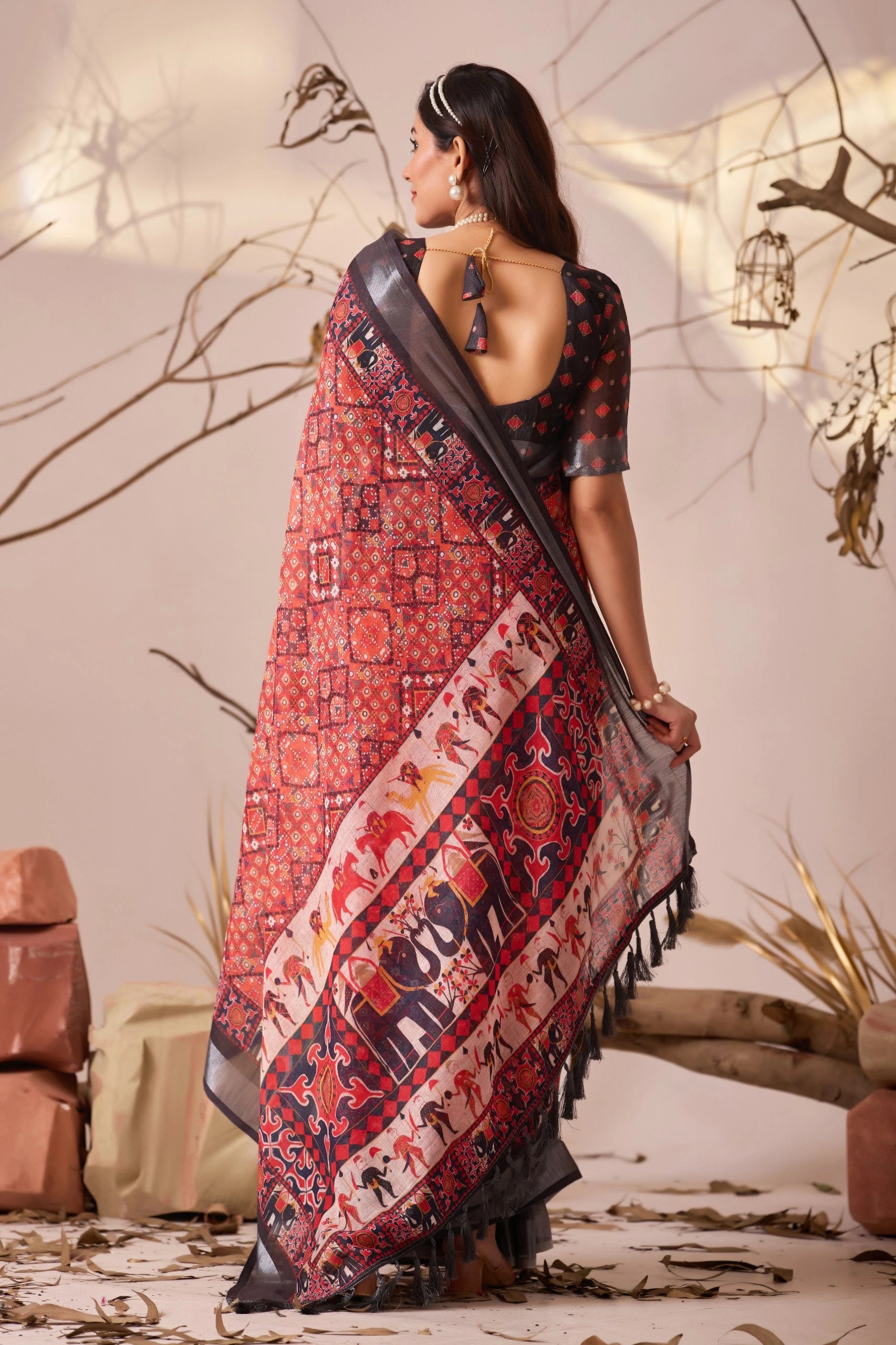 Woman wearing a traditional saree with intricate patterns in a decorative setting.