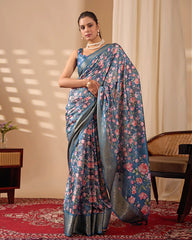 Woman wearing a blue floral saree in an indoor setting with a chair and table.