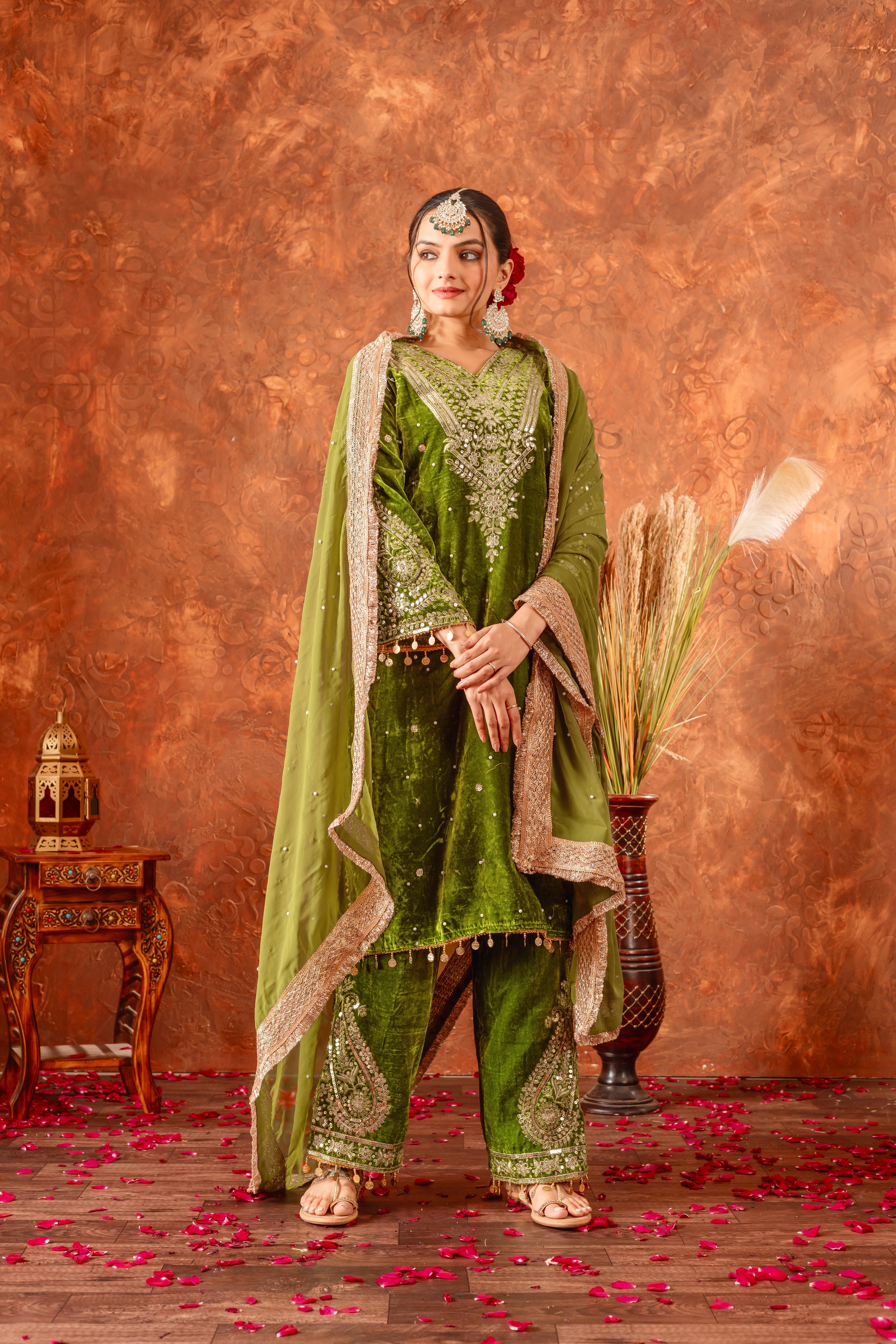 Woman in traditional green and gold outfit with a textured brown background