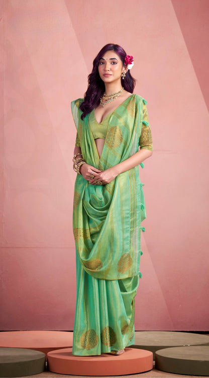 Woman wearing a green saree with gold patterns against a pink background